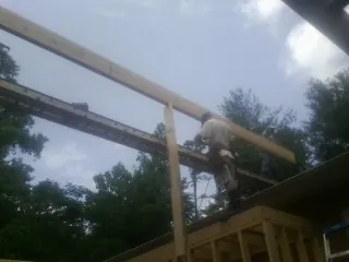 Carpenter setting a ridge beam over a new addition frame — Ice Dam Removal by Roofing Brothers in Spraggs