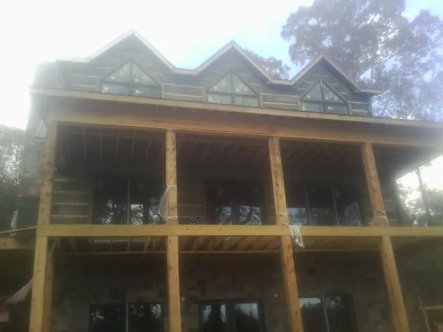 Dormers and porch framing on a large log home under construction — Roof Coating work by our crew in Spraggs