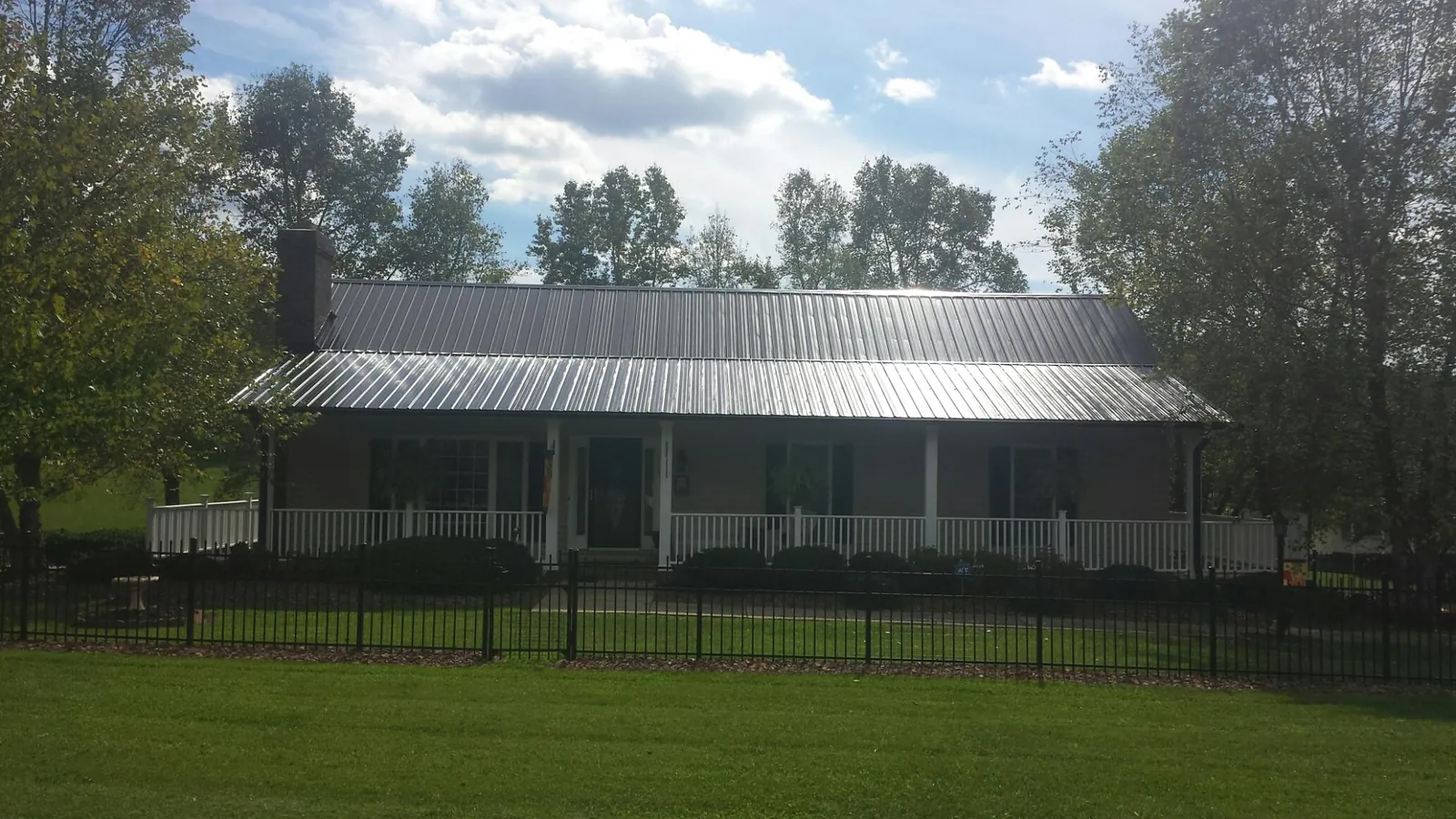 Gray metal roof on a brick ranch with a full width front porch — Gutter Guard Installation work by our crew in Spraggs