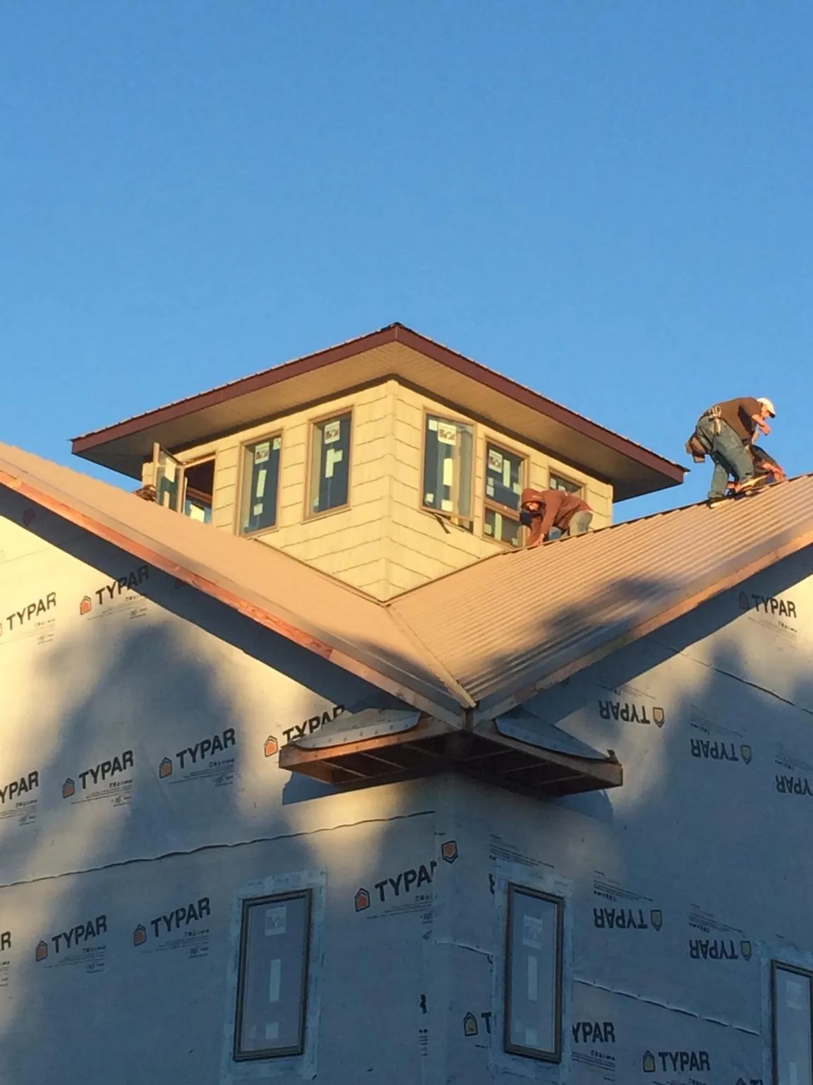 Roofers working around a rooftop cupola on a new metal roof at sunset — Roof Waterproofing in Spraggs by Roofing Brothers